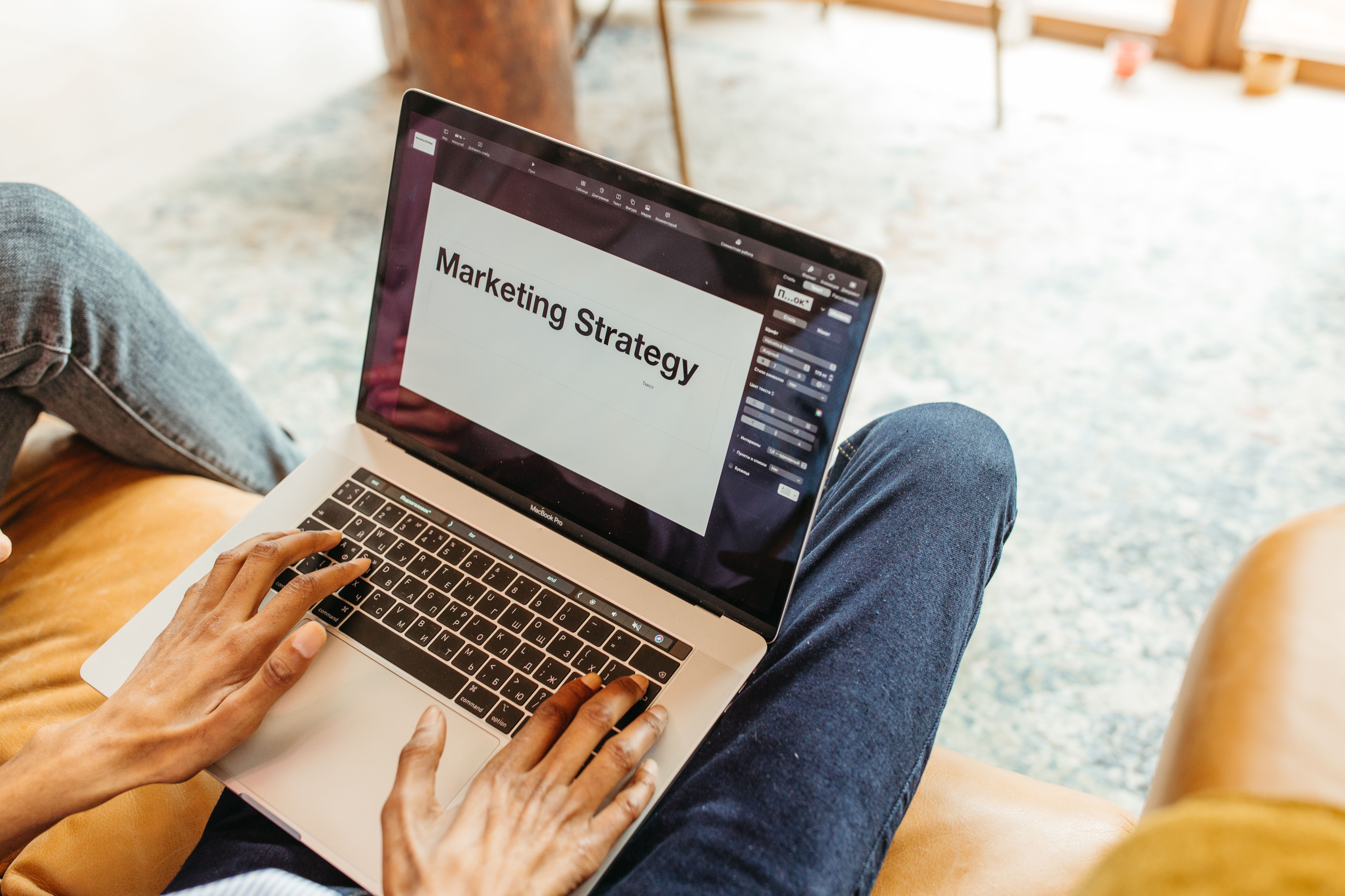 Hands using a laptop displaying a marketing strategy presentation, illustrating AI-assisted ad planning and campaign development.