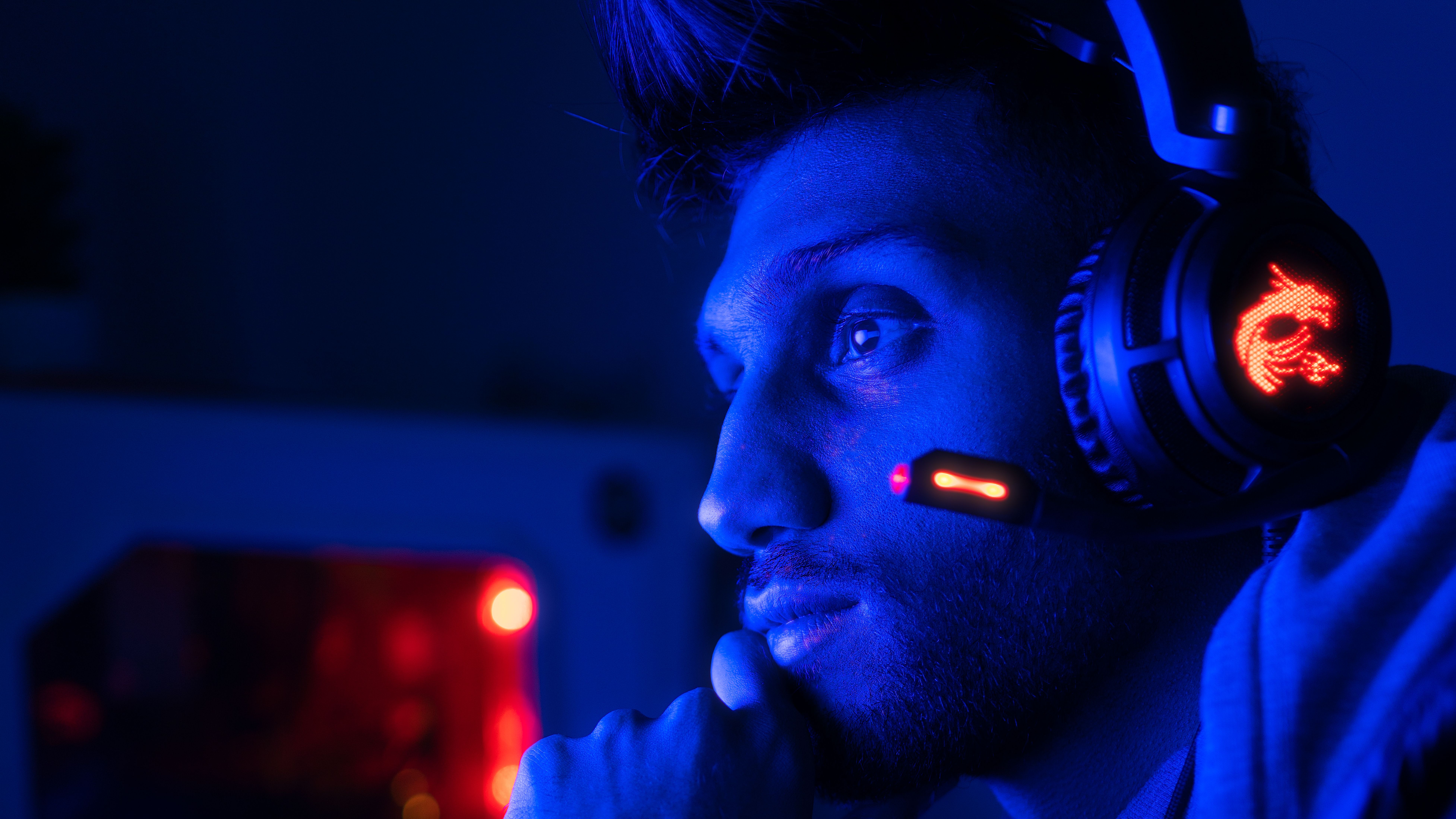 Focused esports gamer wearing a headset under blue lighting, conveying a team’s recognizable gaming identity.
