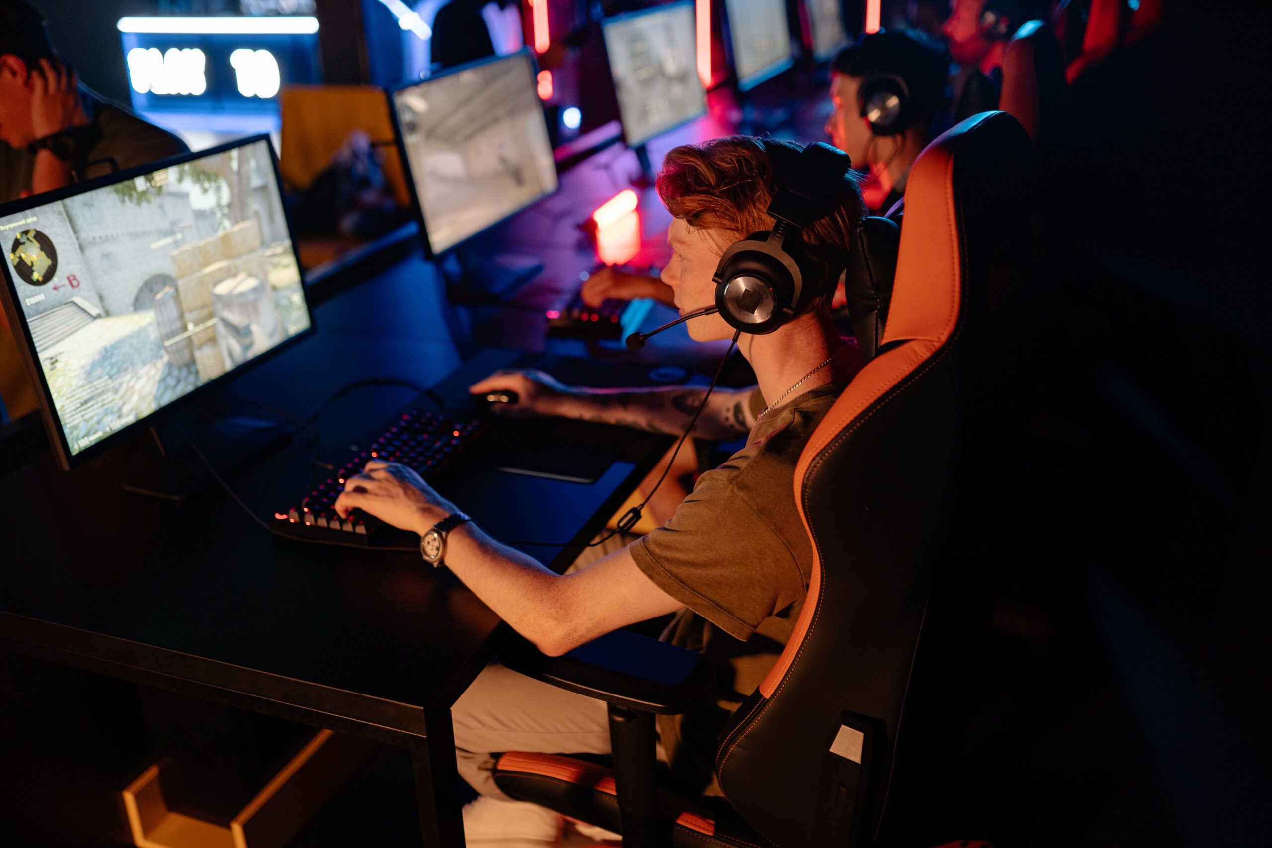 A group of gamers focused on a competitive match in a dimly lit esports arena, representing team coordination and competition.